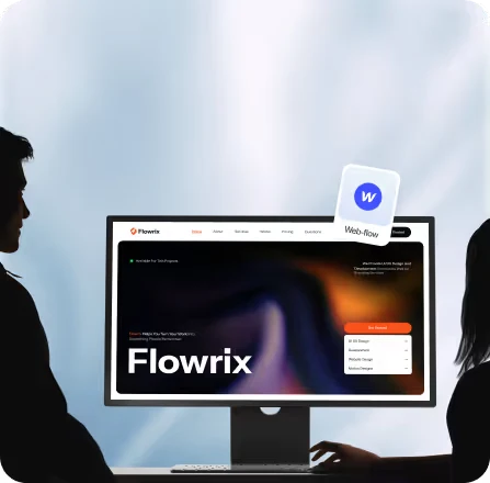 Two people sitting on either side of a desk, facing a computer monitor displaying the Flowrix website homepage.