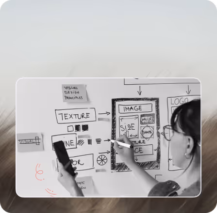 Person wearing glasses drawing a visual design layout with labeled elements like IMAGE, TEXTURE, and LINE on a whiteboard.