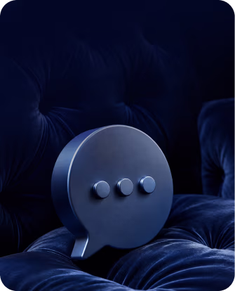 Gray speech bubble icon with three dots on a dark blue velvet tufted cushion.